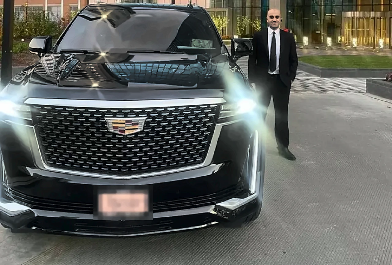 Black Cadillac Escalade with a chauffeur standing at the front